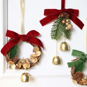 Close-up of Christmas wreath with red velvet bow, gold bells and pine cones