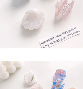 Detailed view of colorful shell-shaped acetate hair claws in pearl white and pink marble