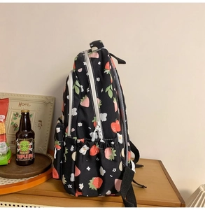 Detail view of black backpack side pocket with cute strawberry and flower pattern print
