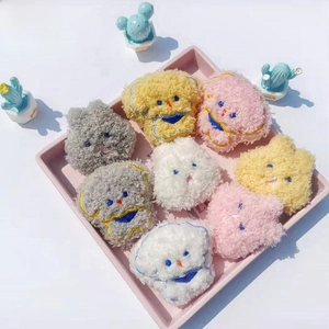 Nahaufnahme von bunten Plüsch-Hunde-Broschen auf einem rosa Tablett mit Bouclé-Details