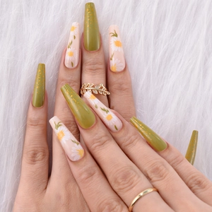 Detail of long coffin press-on nails with avocado green, gold glitter and daisy art