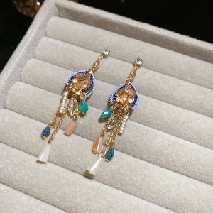 Détail d'une boucle d'oreille bohème à pompons et perles de cristal sur plateau