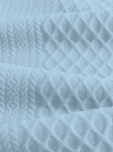 Macro shot of light blue jacquard fabric with waffle knit and cable textures