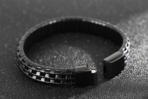 Macro detail of men's black braided leather bracelet with magnetic stainless steel clasp