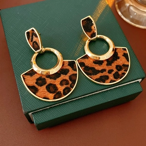 Detail of leopard print fan-shaped earrings on a textured green jewelry box