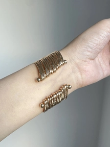 Detailed close-up of a layered gold open cuff bracelet on a model's wrist