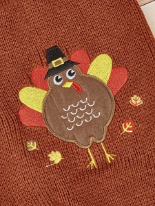 Detailed turkey embroidery and autumn leaves on brown knitted pet sweater fabric