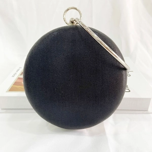 Detail of black round satin evening bag featuring a decorative silver metal ring handle