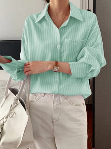 Detail of light green striped long sleeve shirt with classic lapel and button closure