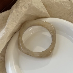 Detailed view of light brown marble texture resin bangle on elegant ceramic plate