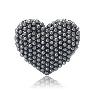 Elegant heart-shaped pearl brooch with grey metal beads and glossy reflection on white surface