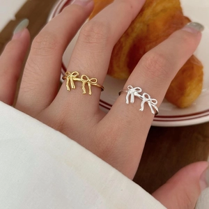 Close-up of gold and silver bow rings on a finger with a lifestyle bakery backdrop