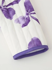 Detail of white quilted coat featuring purple floral print and contrast piping trim