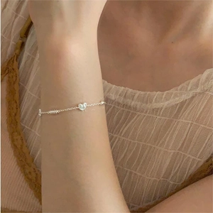 Close-up of S925 sterling silver chain bracelet with heart charm on female wrist
