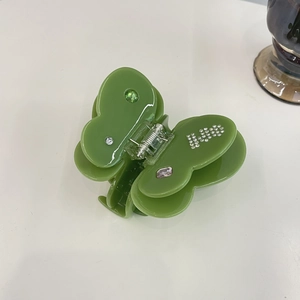 Detailed top view of a green acetate butterfly hair claw clip with colorful rhinestones