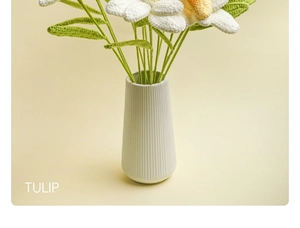 Detailed close-up of a handmade white crochet tulip with yellow core in a ceramic vase