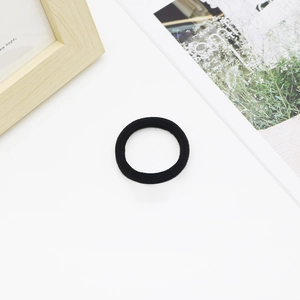 Detail of a black high-elasticity seamless hair tie on a minimalist lifestyle background