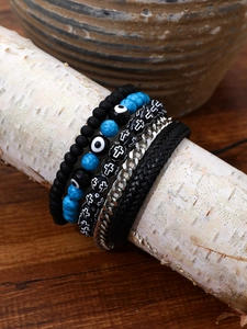 Detail of layered hip-hop bracelets with beads, blue turquoise, and woven leather on wood