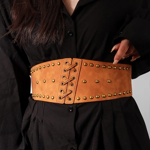 Close-up of brown leather corset belt with gold studs and front lace-up detail on model