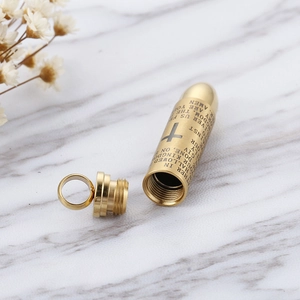 Golden stainless steel cross bullet pendant with engraved Lord’s Prayer on marble background