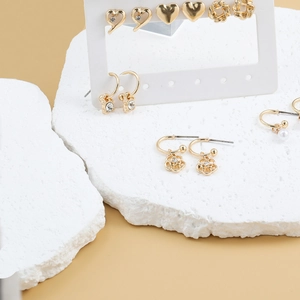 9-pair set of gold fashion earrings featuring pearls, hearts, and floral designs on a display