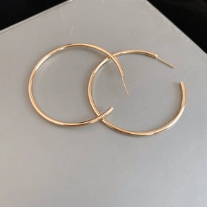 Close-up of high-polish large golden hoop earrings with minimalist circular design