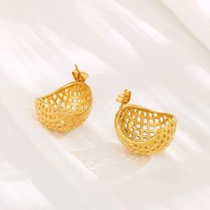Detailed macro view of 18K gold hollow woven mesh stud earrings on white silk fabric