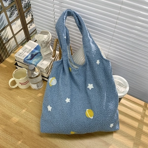 Detail view of navy fleece tote bag with star embroidery and artistic still life scene