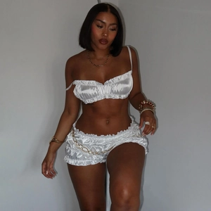 Detail of white satin camisole top and ruffled shorts set with silk luster texture