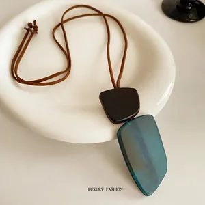 Irregular geometric pendant necklace with blue resin and dark matte finish on ceramic tray
