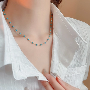 Detail of bohemian gold plated necklace featuring small blue turquoise beads on a model