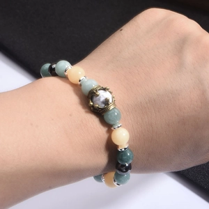 Dettaglio del bracciale con perline, corona dorata e pietre di ossidiana multicolore