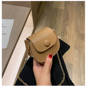 Gros plan du mini sac selle en cuir fauve avec bandoulière en chaîne dorée et rabat aimanté