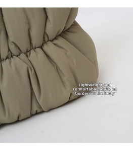 Detail shot of olive green puffer bag featuring elastic drawstring hem and puffy texture