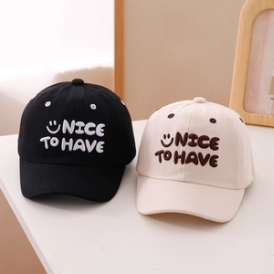 Close-up of embroidered smile face and letters on cotton baseball caps for kids