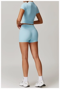 Rear view of light blue high-waist sports shorts and cropped top on a fit female model