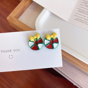 Gros plan de boucles d'oreilles de Noël festives en émail rouge et vert avec nœuds