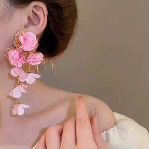 Detail of pink chiffon fabric flower earrings with tassel petals and golden hardware