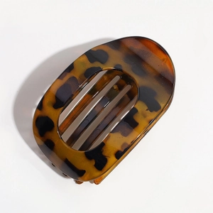 Detail view of a leopard print acetate claw clip with a sleek oval-shaped hollow design