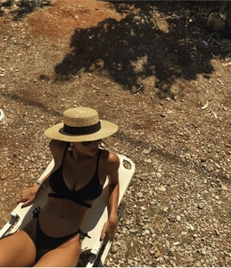 Flat top straw boater hat with black ribbon and black string bikini on beach lounger
