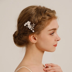 Détail d'un peigne à cheveux de mariée avec fleurs en céramique blanche et strass