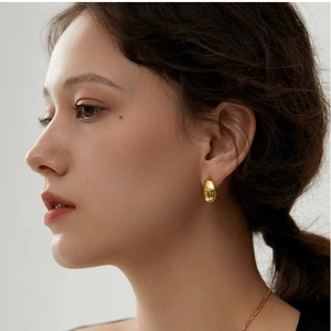 Close-up of elegant chunky gold hoop earrings worn on a model for a minimalist style