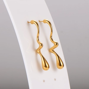 Detail of elegant gold wave drop earrings featuring sleek irregular curves on card