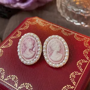 French vintage cameo earrings with pearl border on a red textured jewelry box