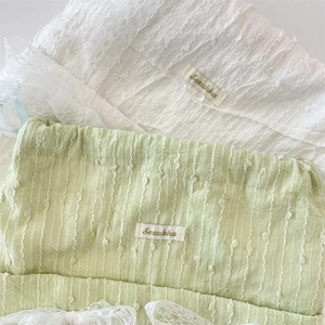 Close-up of floral embroidery on light green canvas and white lace textured drawstring bag
