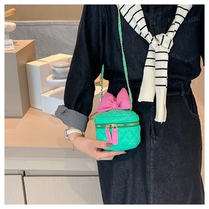 Detail of green quilted girl's purse with large pink bow and gold chain strap