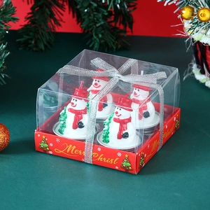 Close-up of four cute snowman candles in a transparent gift box with silver ribbon bow