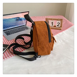 Detail view of caramel corduroy backpack with adjustable nylon straps on a desk