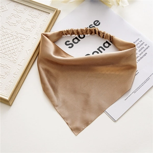Detail of golden satin hair scarf with elastic band on a decorative white surface