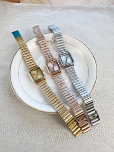 Detailed shot of three square dial watches in gold, rose gold and silver on a decorative plate